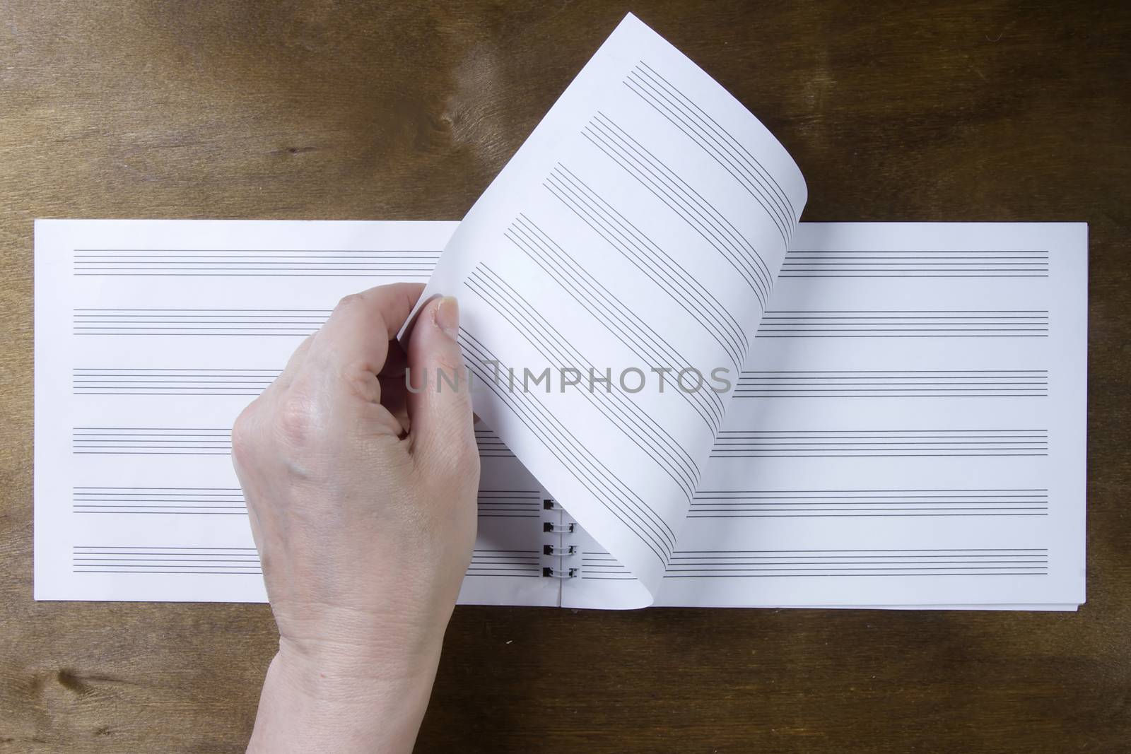 Hand turns over the pages of a notebook on a wooden background