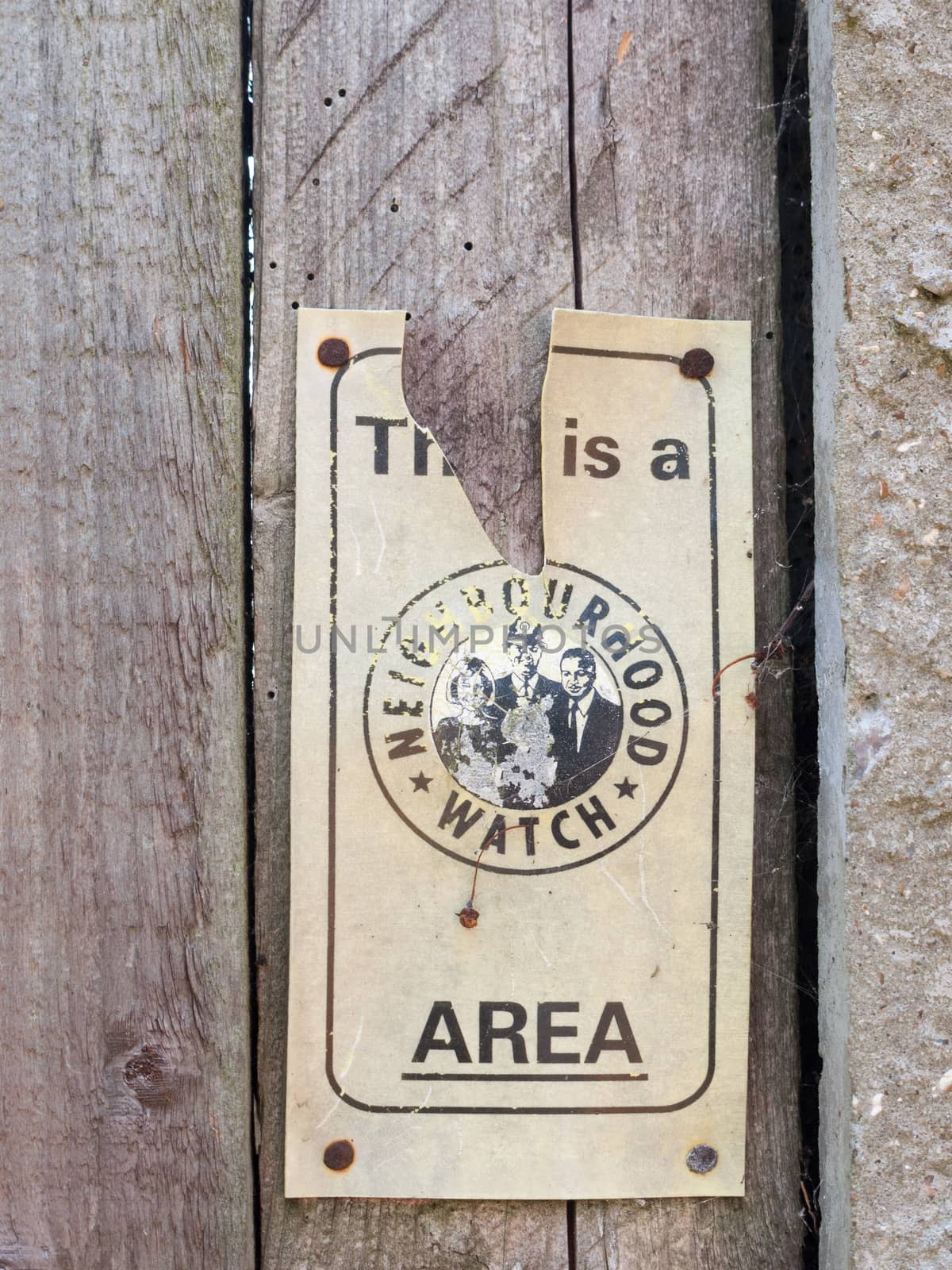 a broken neighborhood watch sign area outside on fence