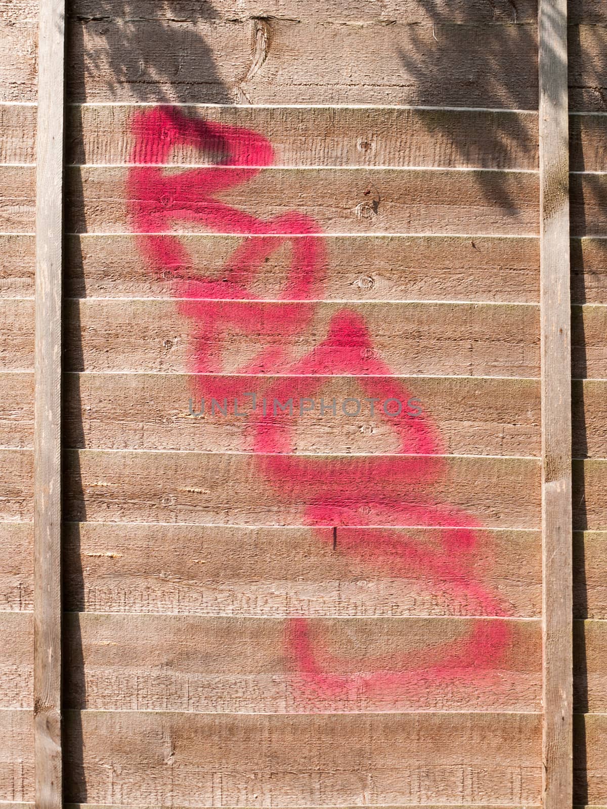 a red spray paint stain outside on a wooden garden fence