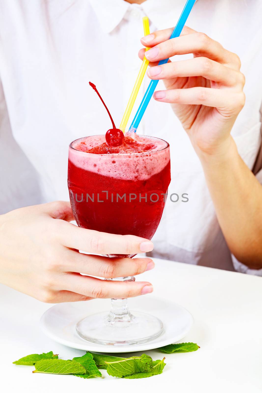 Cherry smoothie in a big glass cup with two straws in woman's hands. Lady with a drink
