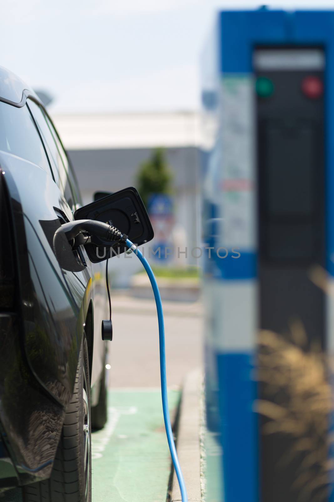 Power supply for electric car charging. Electric car charging station. Close up of the power supply plugged into an electric car being charged.