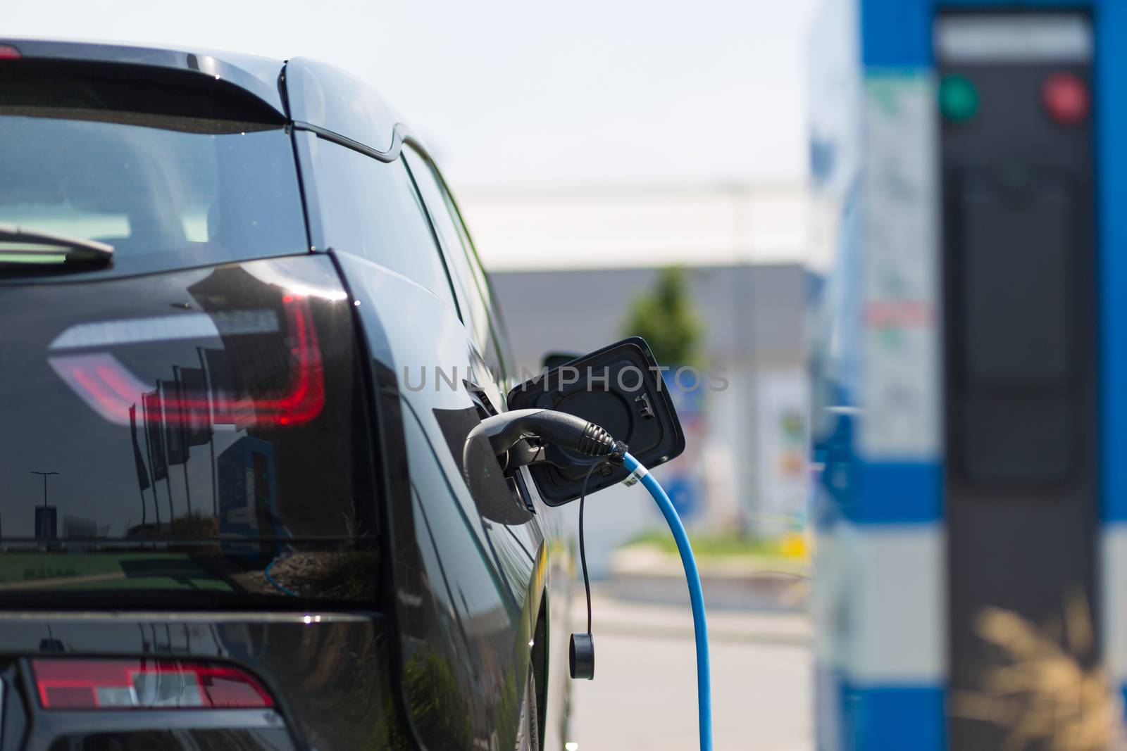 Power supply for electric car charging. Electric car charging station. Close up of the power supply plugged into an electric car being charged.