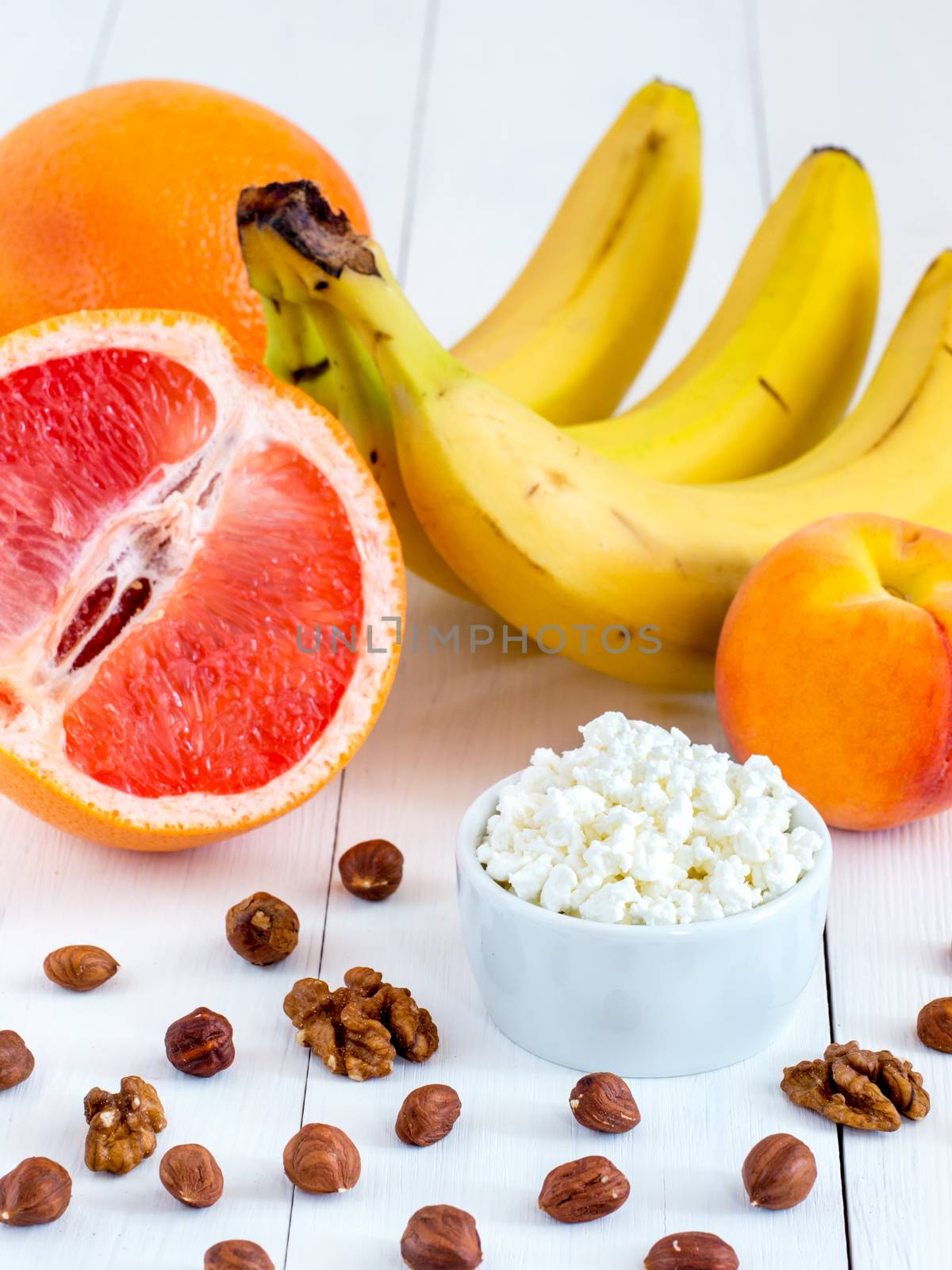 Healthy breakfast: cottage cheese, fruits and nuts on white wooden background. Dieting, healthy lifestyle concept meal. Vertical