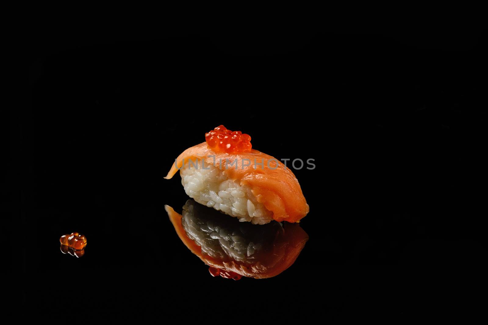 Sushi and red caviar of salmons on black acryle with reflection