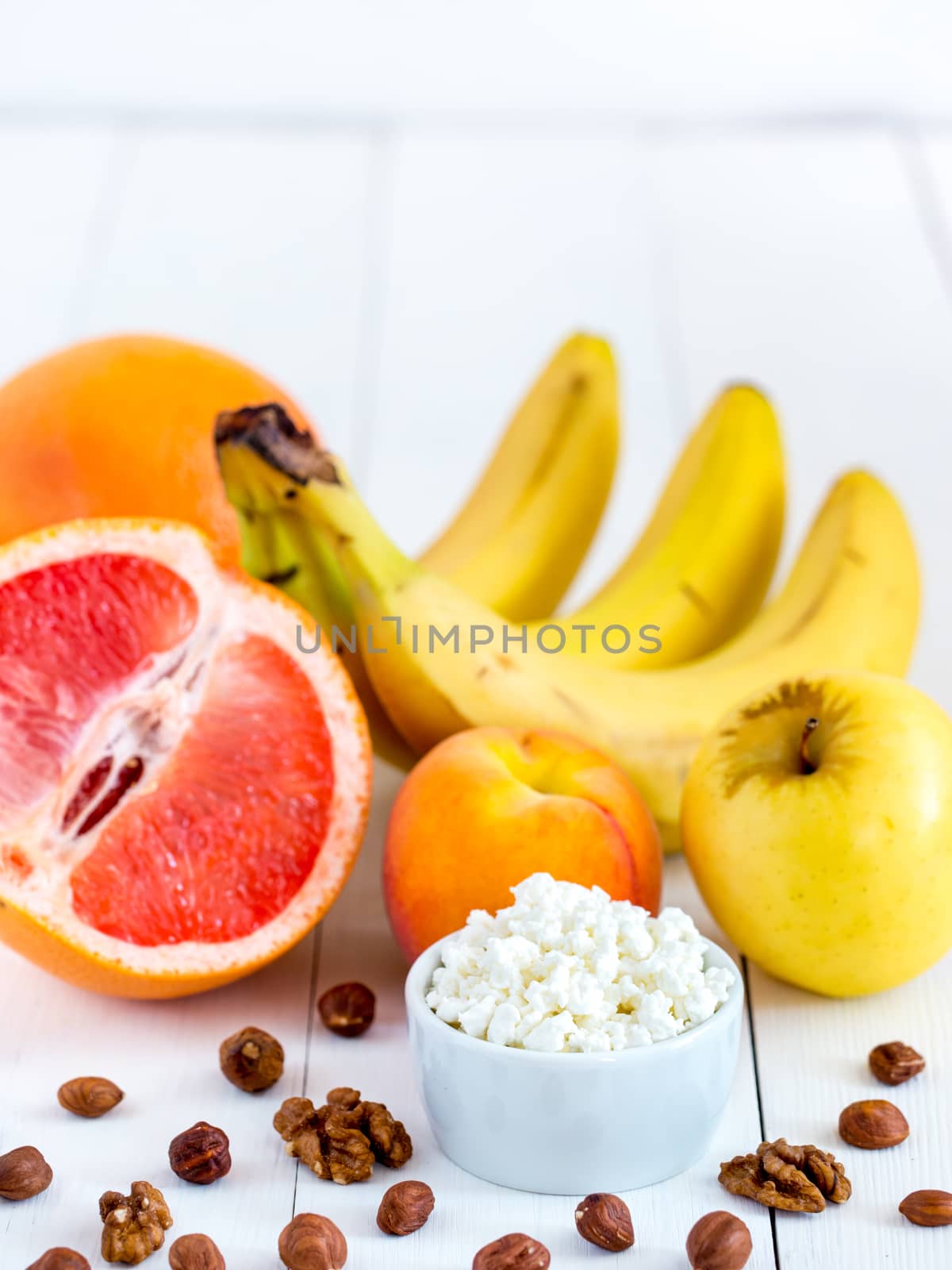 Healthy breakfast: cottage cheese, fruits and nuts on white wooden background. Dieting, healthy lifestyle concept meal. Vertical with copyspace