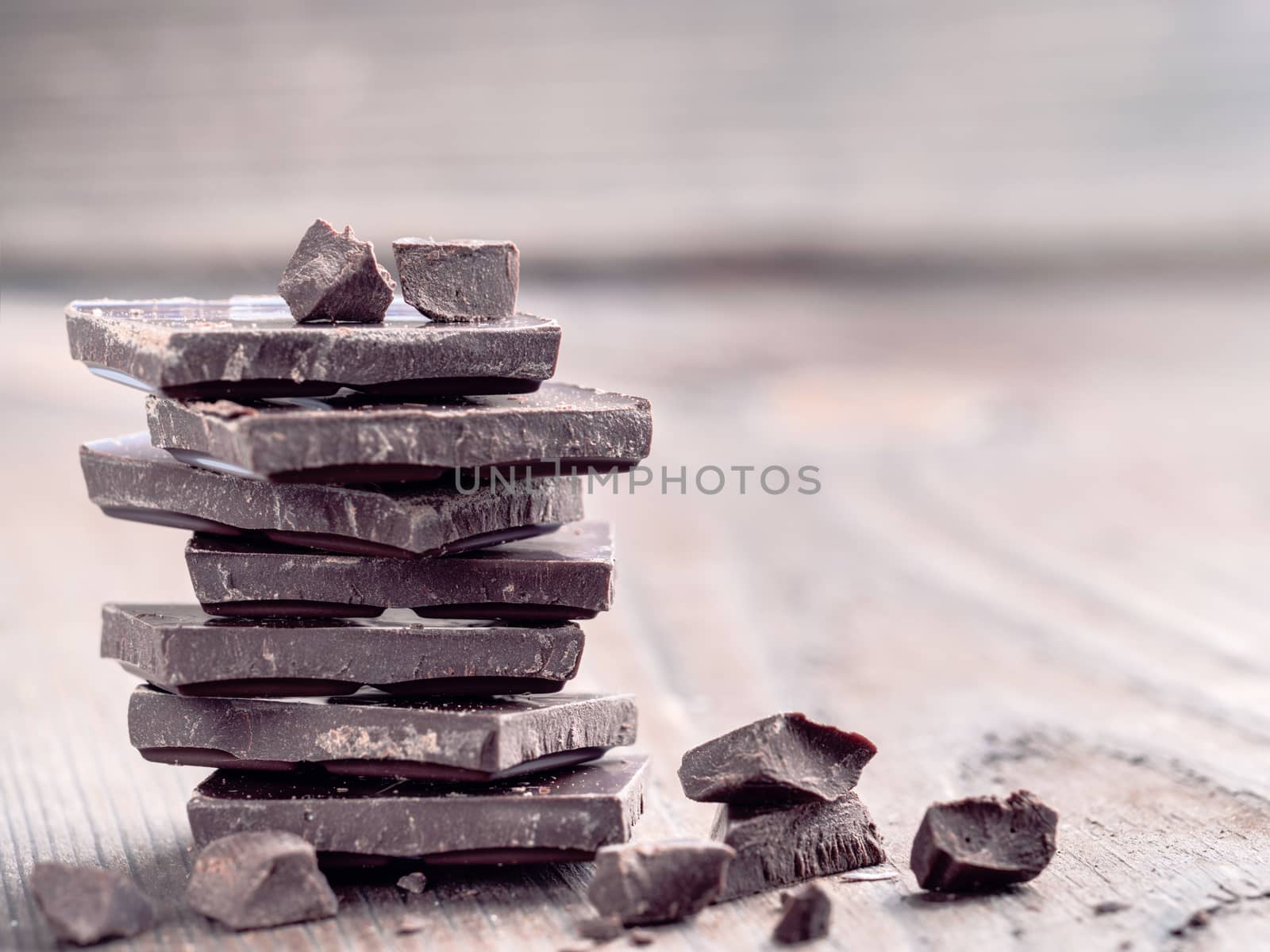 Stack of dark chocolate with copy space. Chocolate with chunks and crumbs on wooden background.
