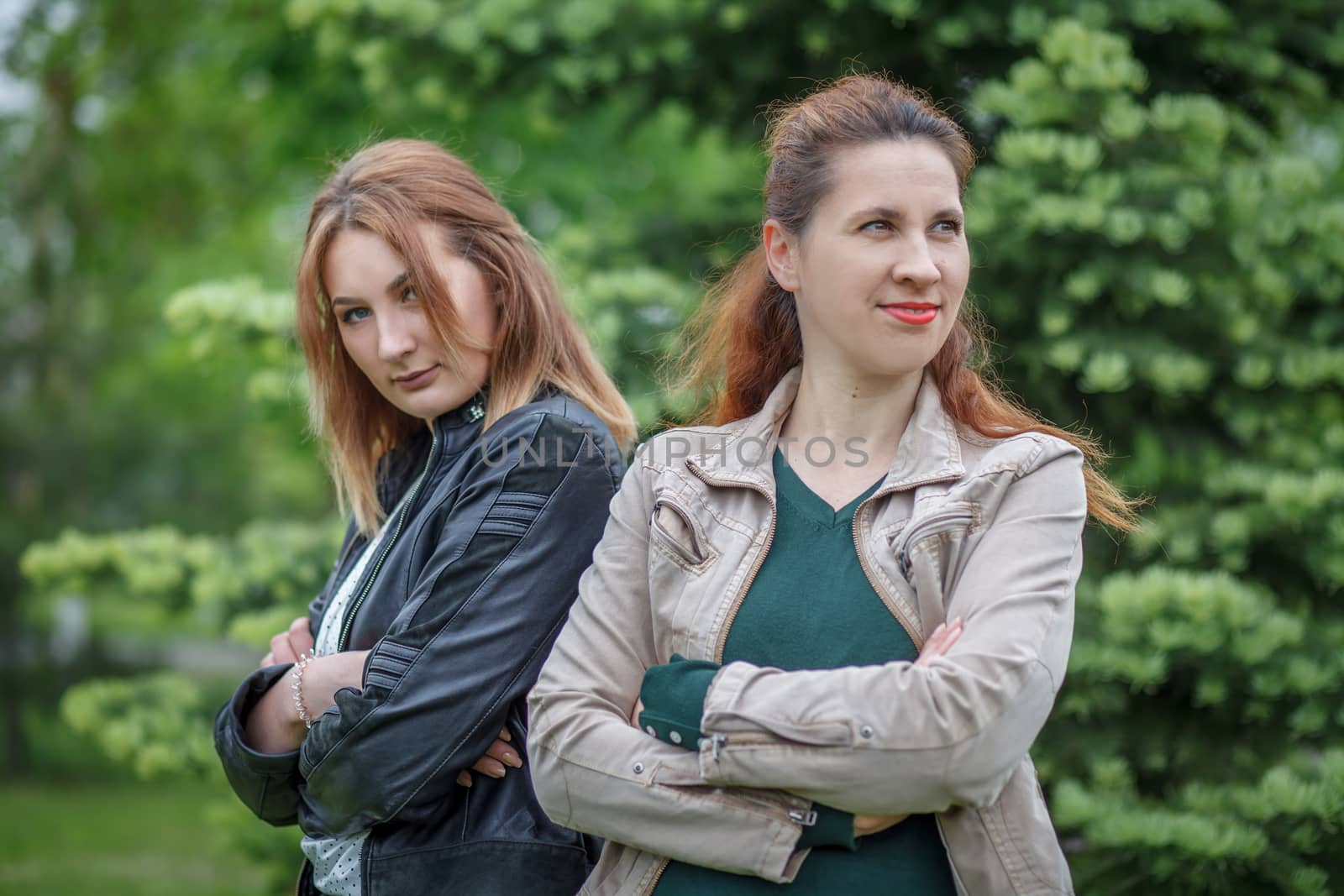 Mother with daughter standing back-to-back in park together