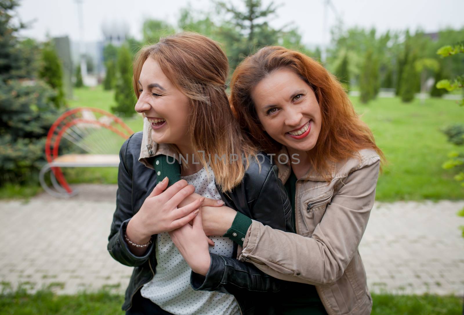 Two laughing women hugging outdoor