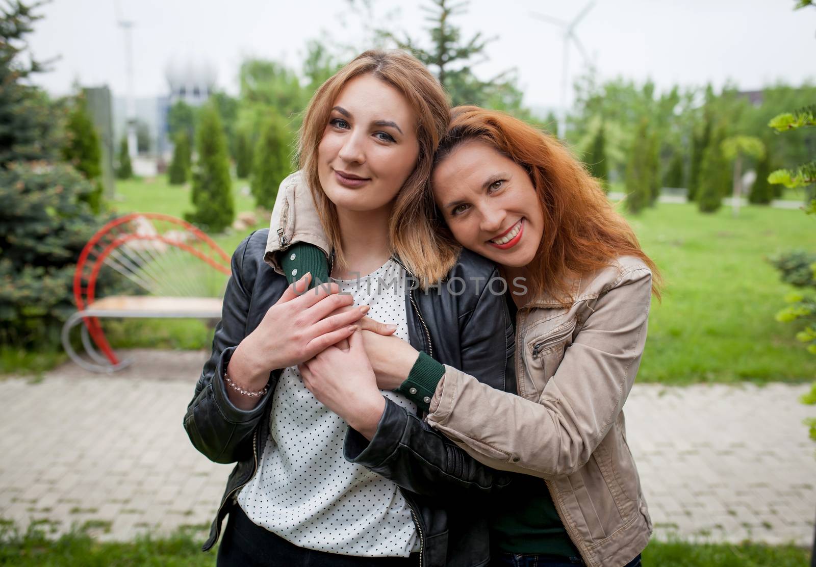 Two happy affectionate women friends hugging outdoors