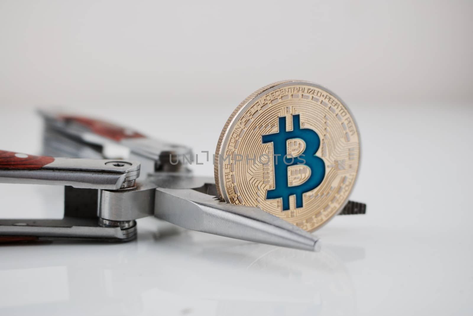 Cryptocurrency physical gold bitcoin coin and pocket knife on the table.
