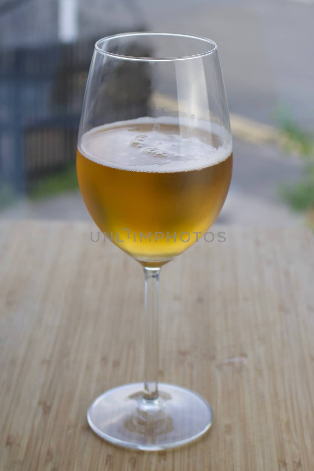 Gold beer in glass on the wooden table near window at home.