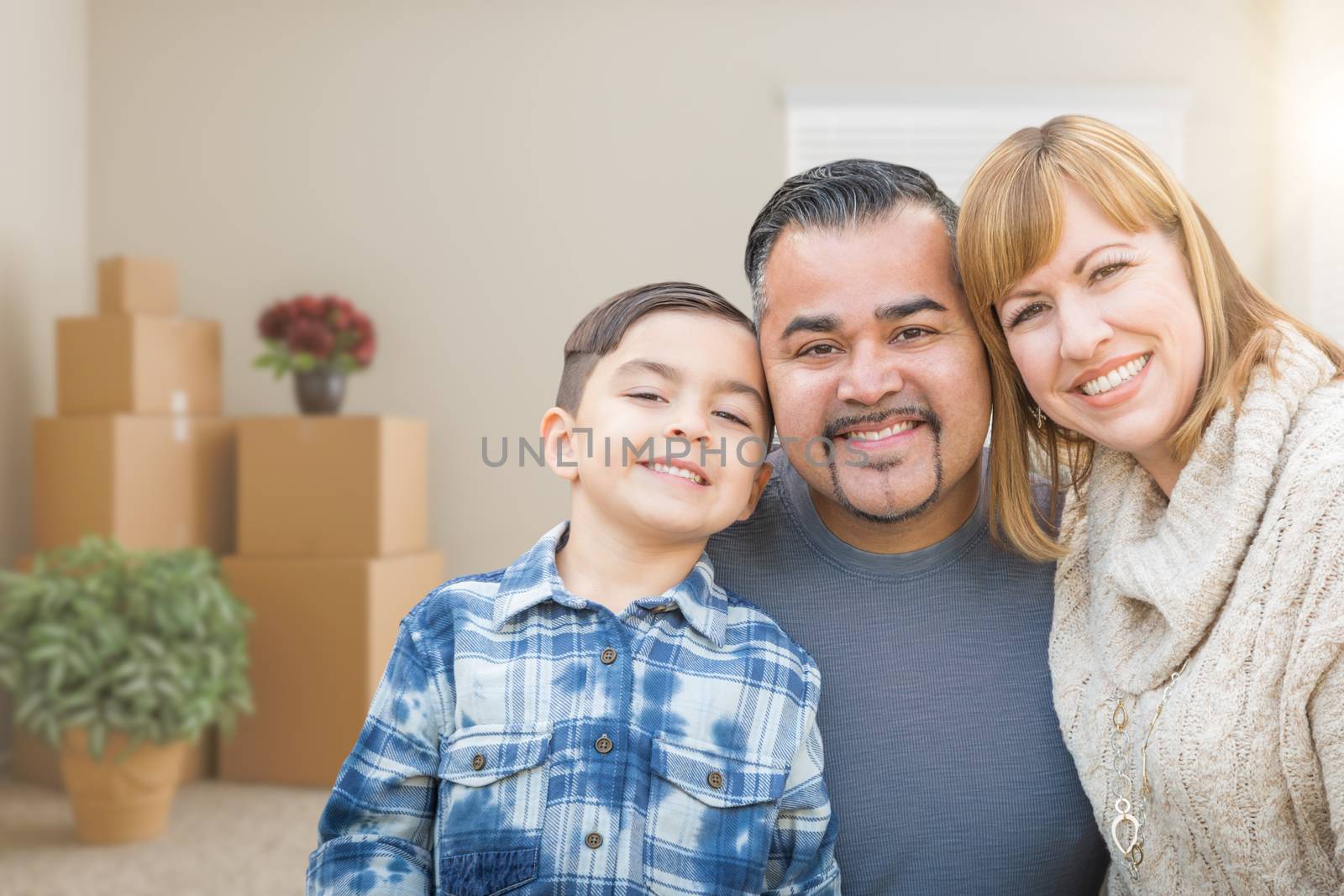 Mixed Race Family In Empty Room With Moving Boxes and Plants. by Feverpitched