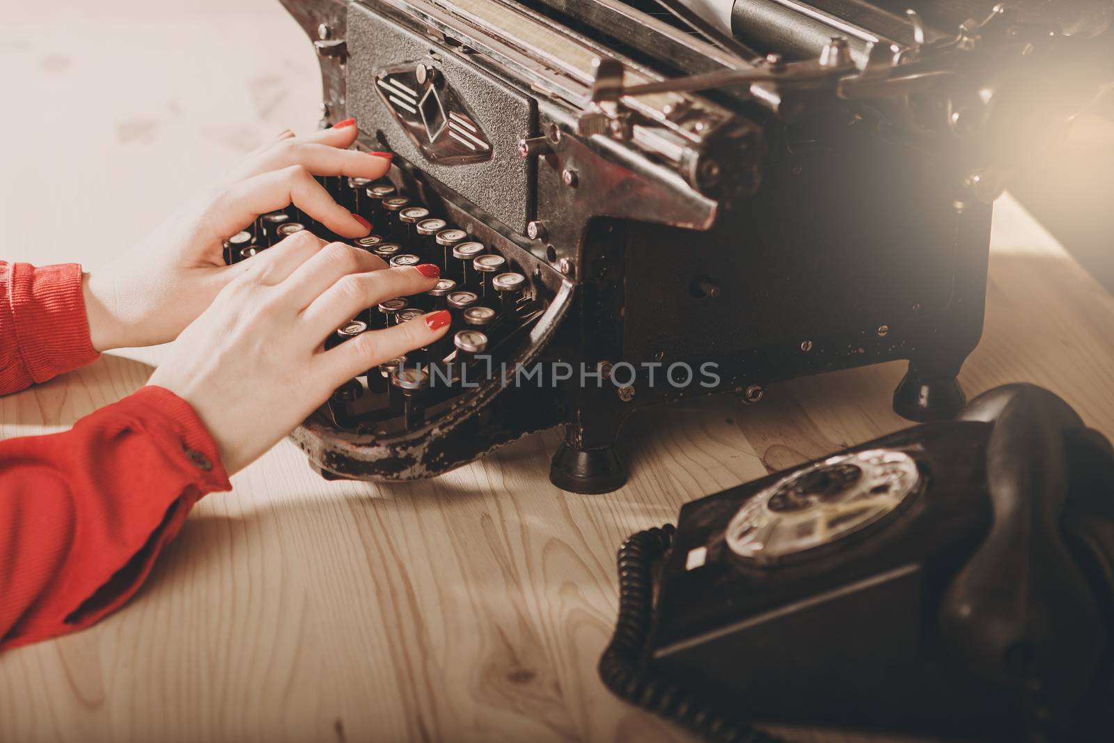 Secretary at old typewriter with telephone. Young woman using typewriter. Business concepts. Retro picture style.