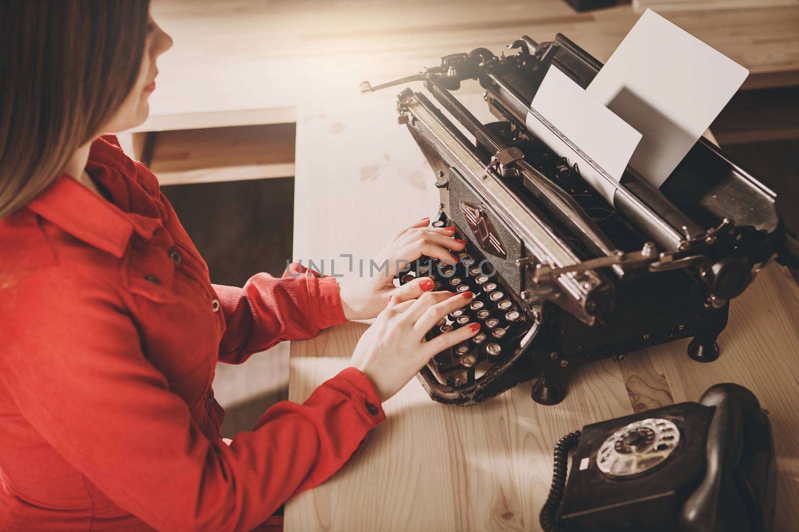 Secretary at old typewriter with telephone. Young woman using ty by natazhekova