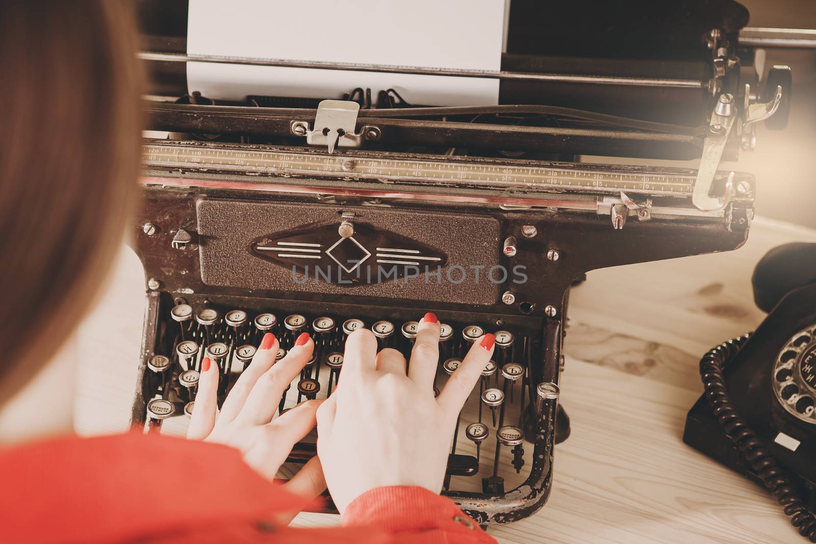 Secretary at old typewriter with telephone. Young woman using ty by natazhekova