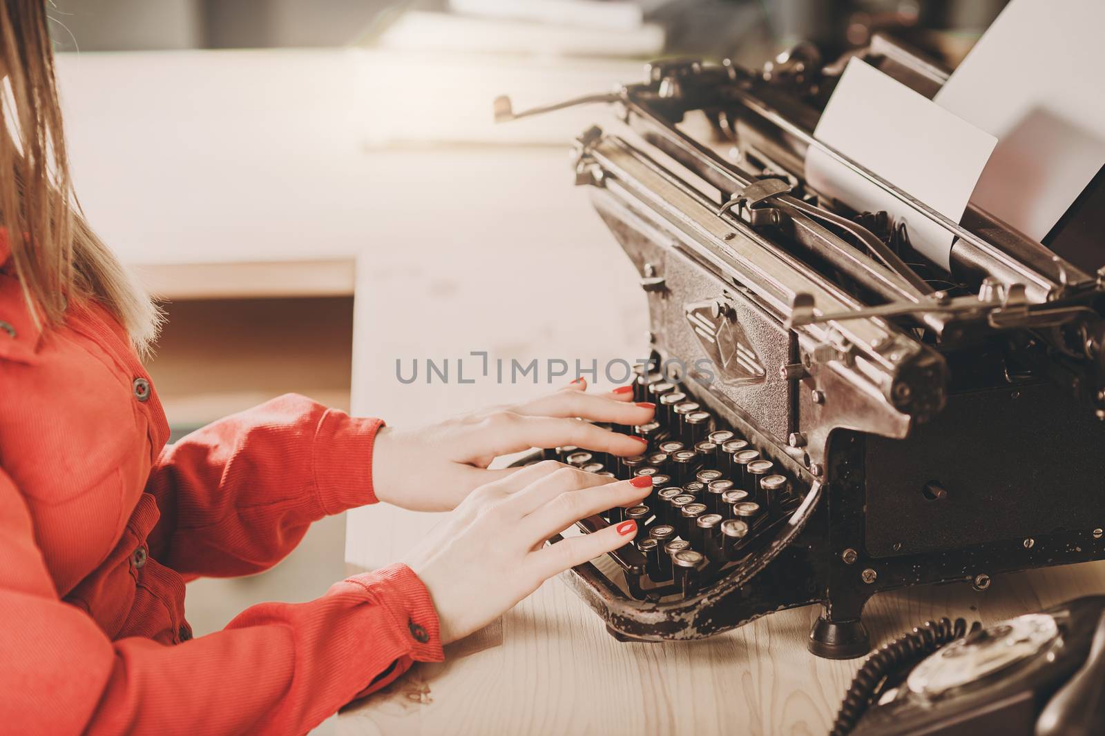 Secretary at old typewriter with telephone. Young woman using typewriter. Business concepts. Retro picture style.