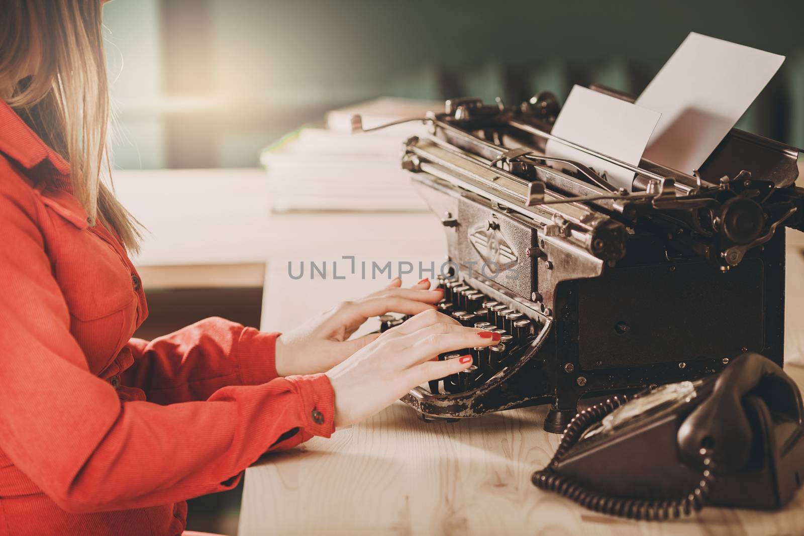 Secretary at old typewriter with telephone. Young woman using ty by natazhekova