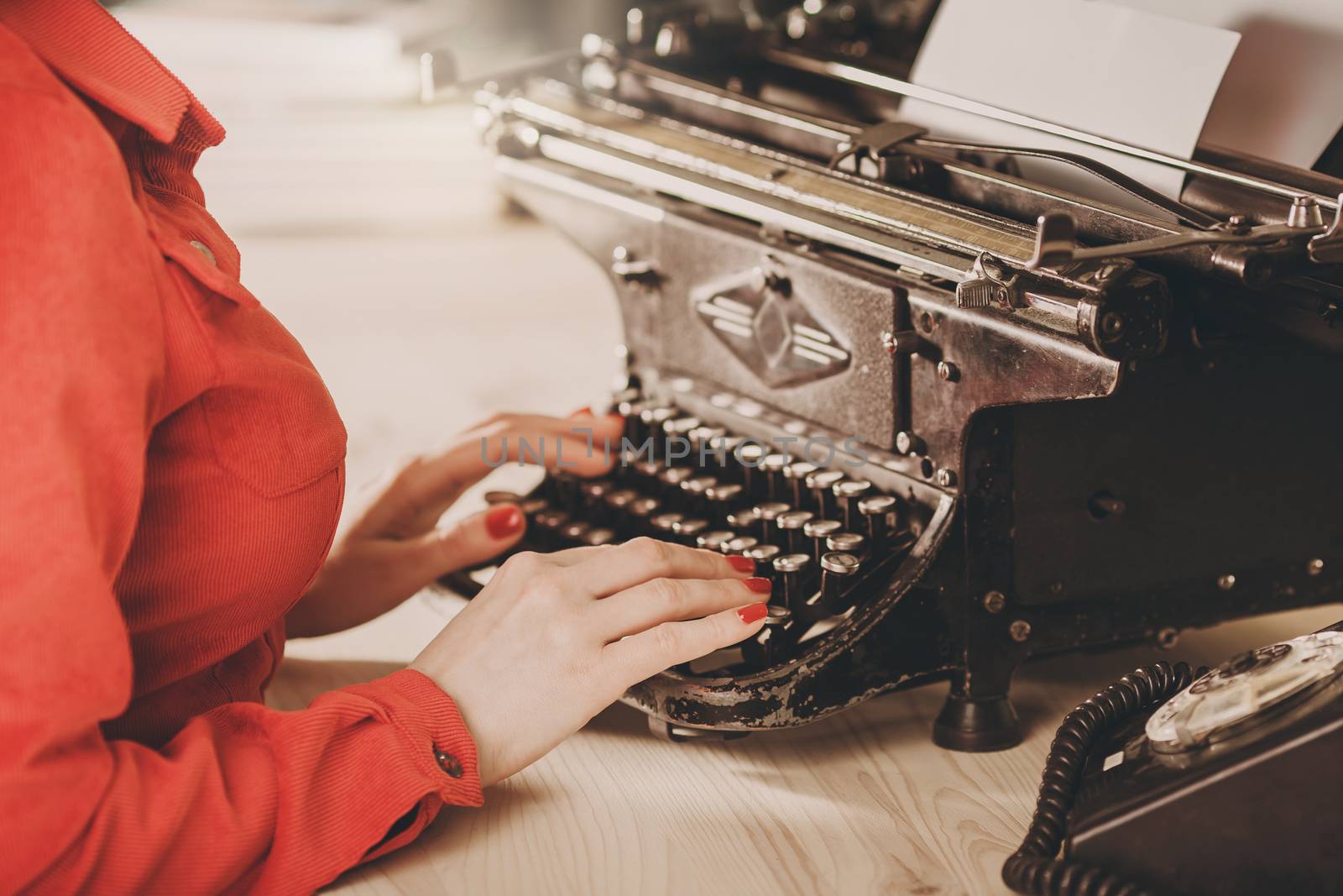 Secretary at old typewriter with telephone. Young woman using typewriter. Business concepts. Retro picture style.