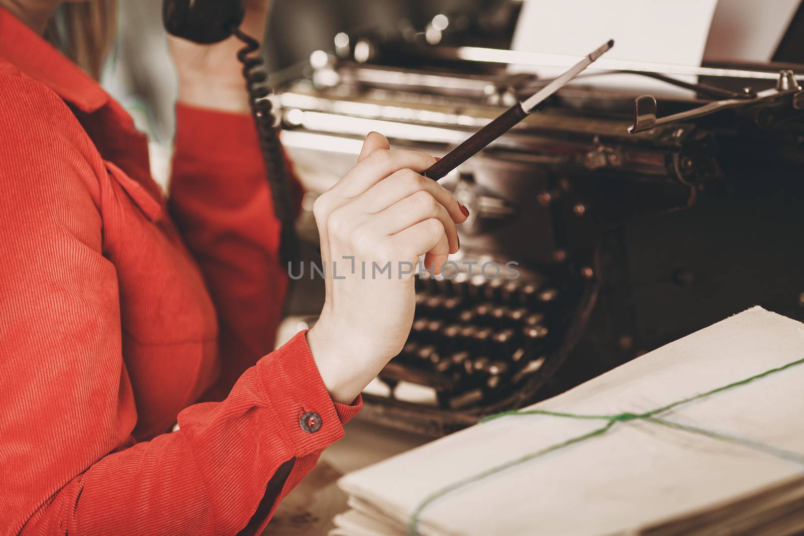 Secretary at old typewriter with telephone. Young woman using typewriter. Business concepts. Retro picture style.