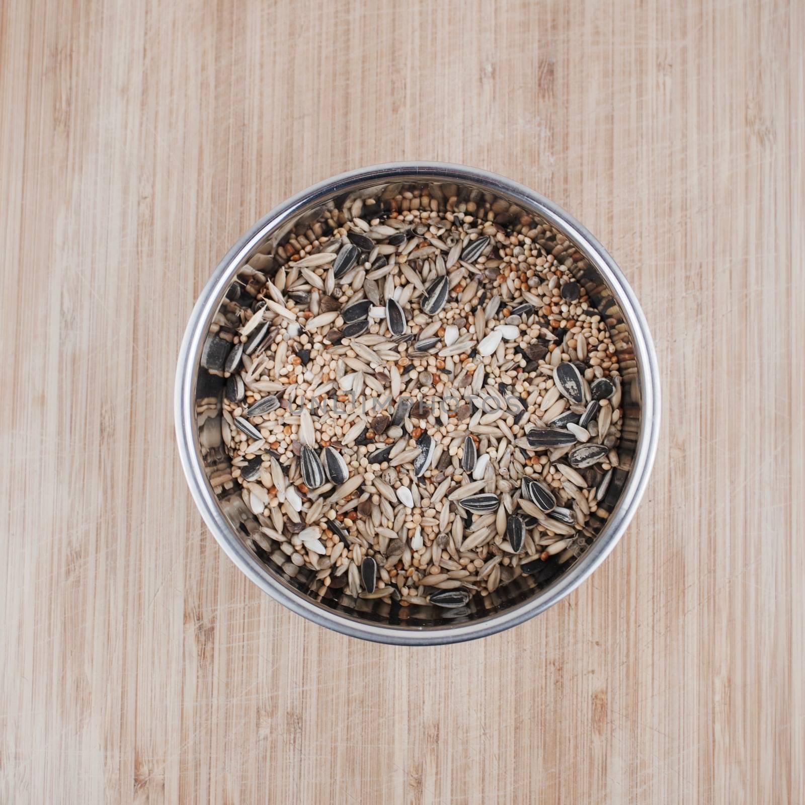 Fresh and healthy seeds in metal chrome container on the wooden board in the kitchen.