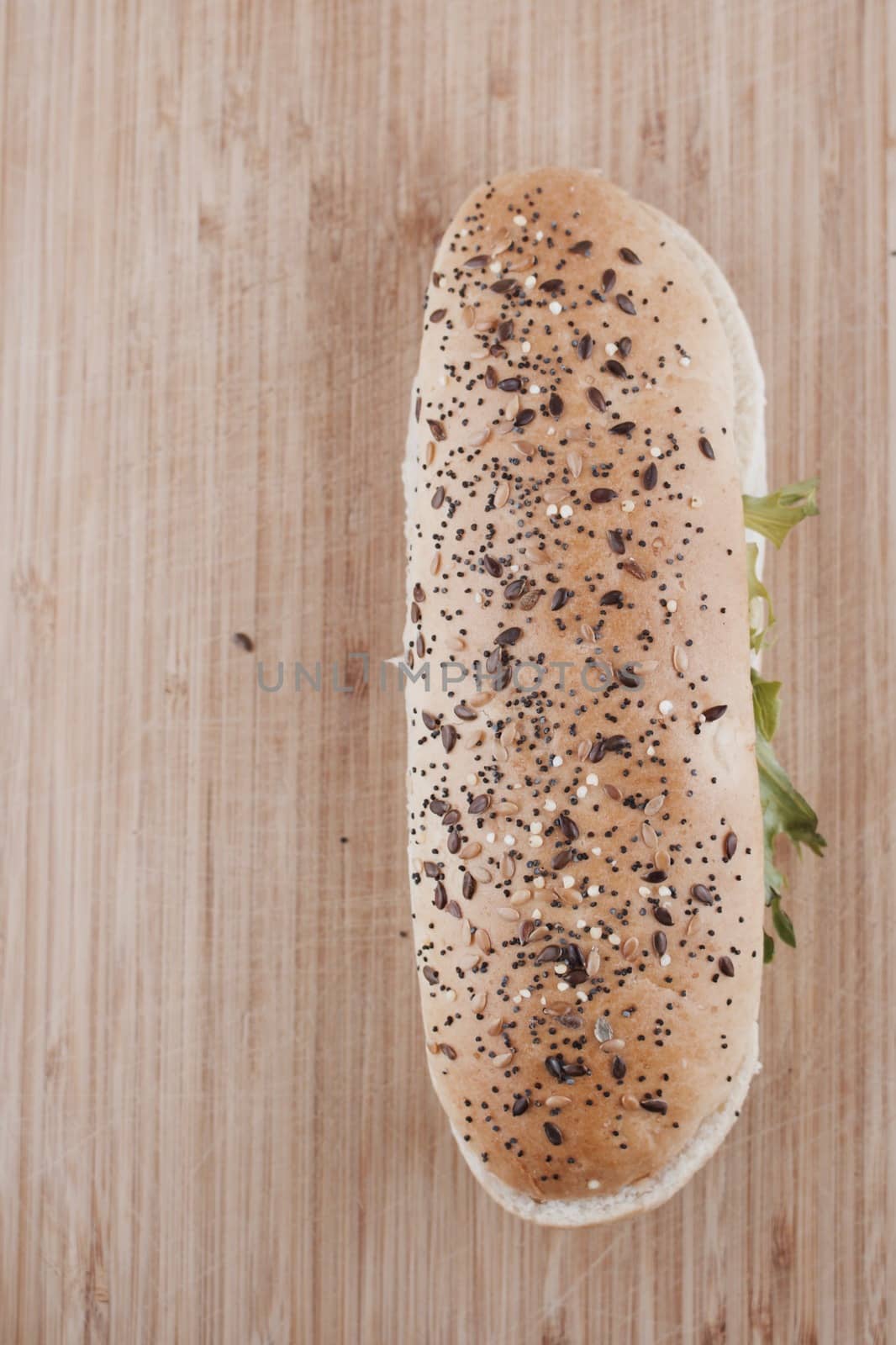Long roll with seeds, tuna and salad on the wooden board in the kitchen.