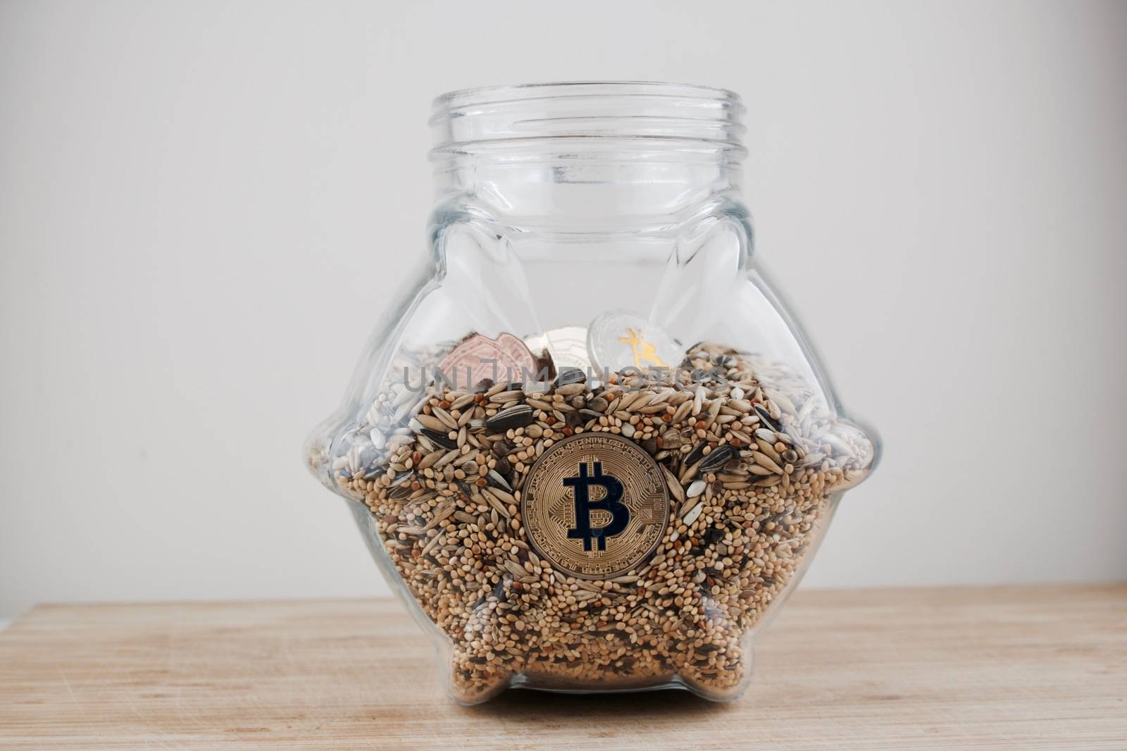 Cryptocurrency physical gold silver and brass bitcoins in glass jar on the wooden table.