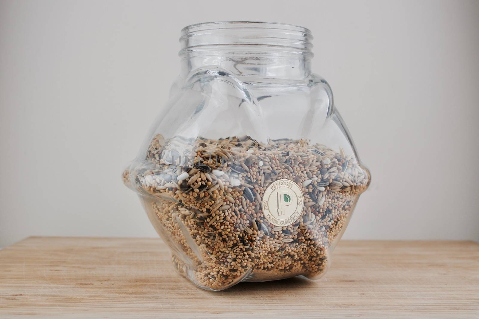 Digital currency physical gold peercoin coin in glass jar with fresh seeds.