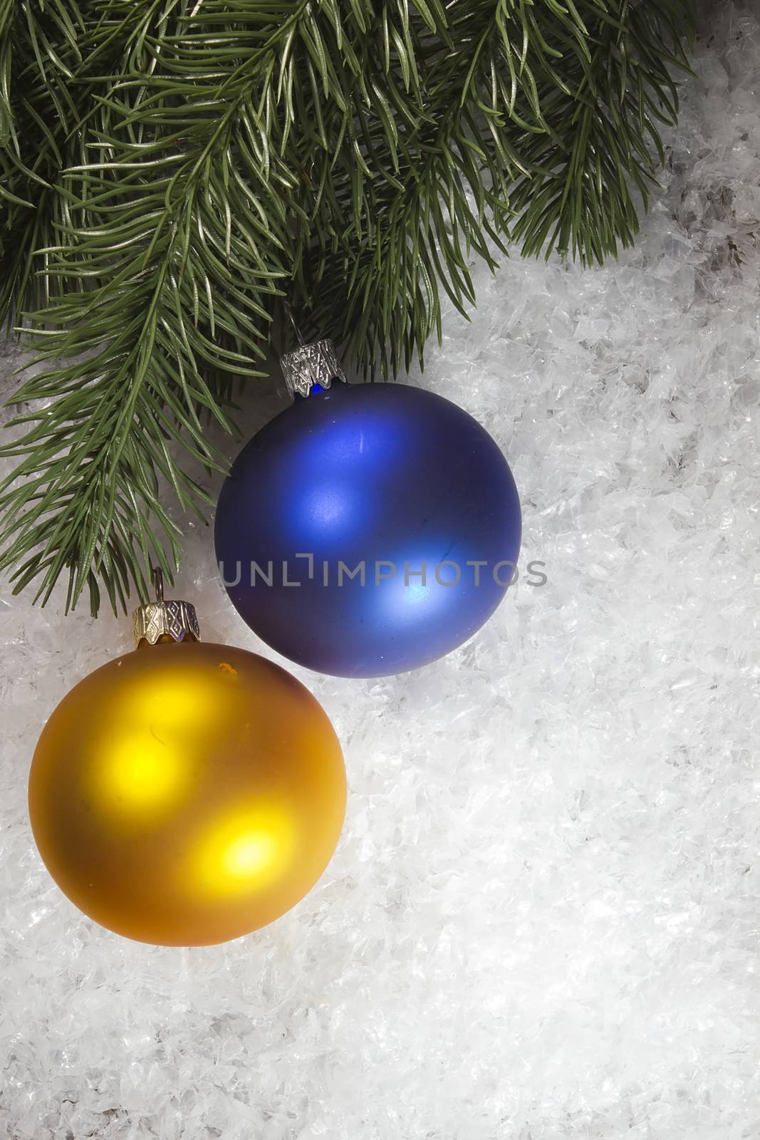 Multicolored balls and fir branch on snow