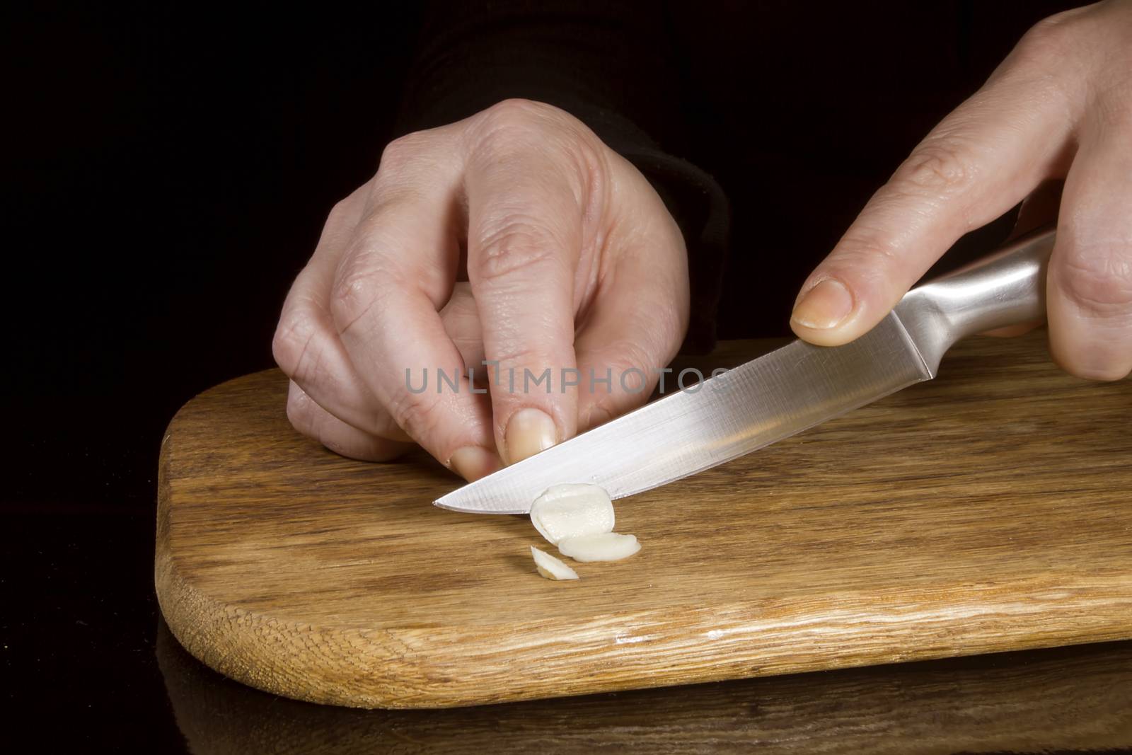 Woman chopping garlic with a knife by VIPDesignUSA