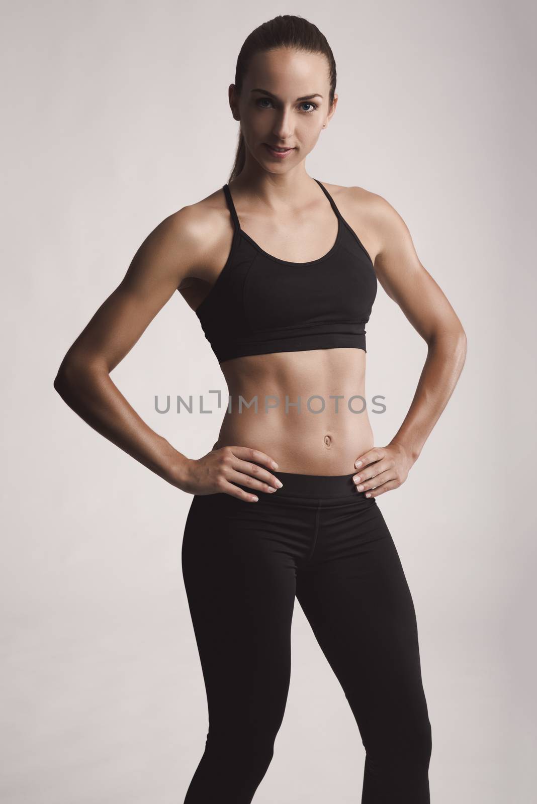 Portrait of sporty young woman with muscular body looking at camera confidently
