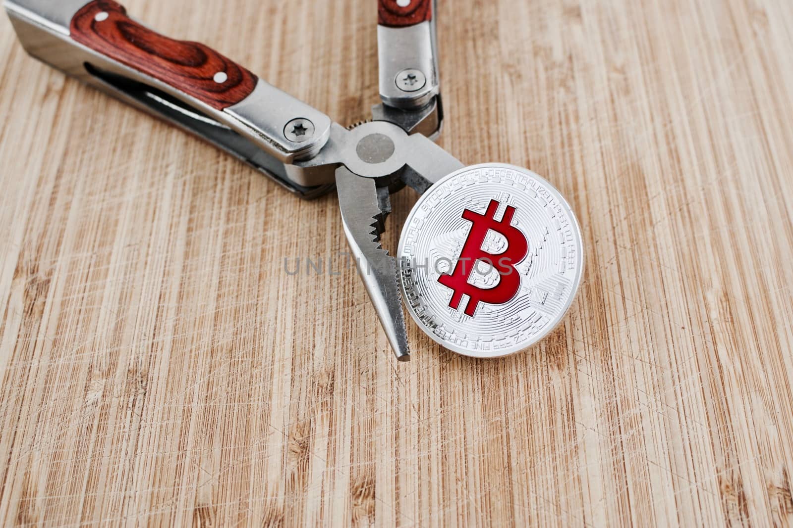 Digital currency physical red bitcoin coin on the wooden board. Pocket Knife.