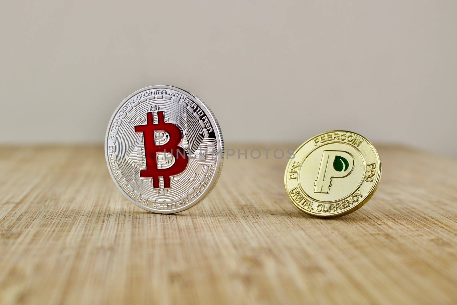 Digital currency physical silver bitcoin coin and gold peercoin on the wooden board.