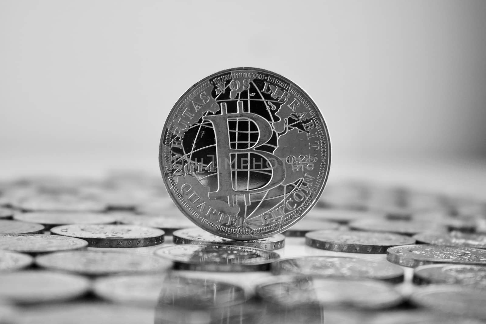 Digital currency physical silver bitcoin coin in black and white scene.