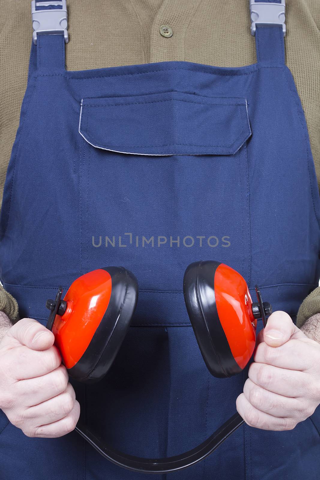 Protective headphones in the hands of a worker in blue overalls