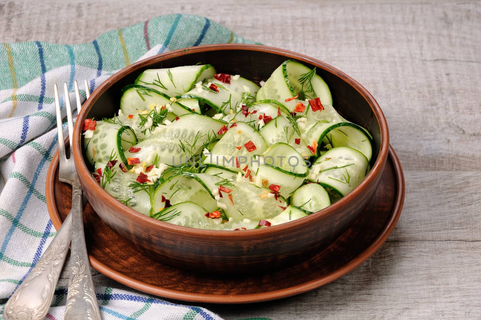 A bowl of salad from cucumber strips with spices, garlic and dill. Rustic style.
