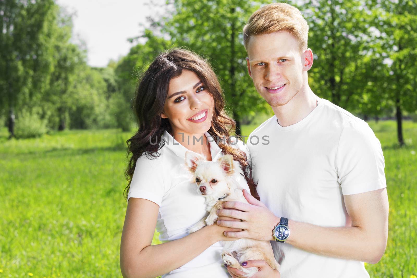 Happy smiling young couple with their dog in park