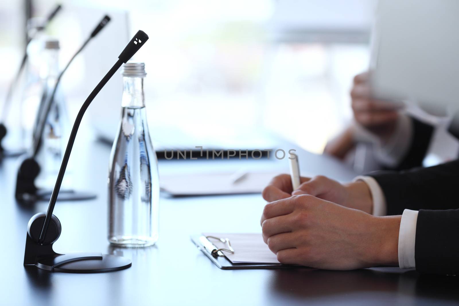 Group of speakers at business meeting at the table with microphones