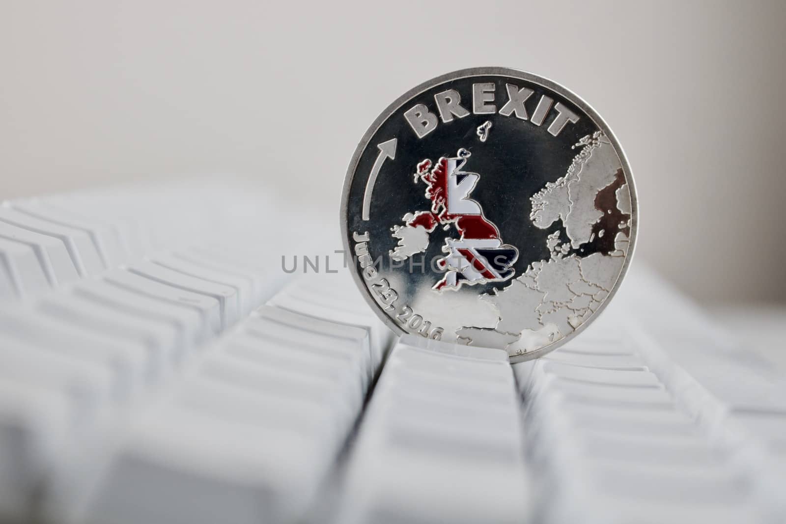 Europe leaving. Brexit physical coin on the white keyboard. British map.