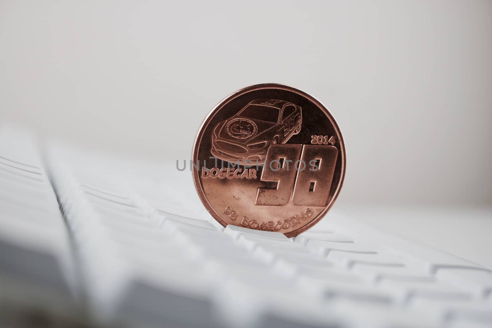Digital currency physical brass dogecoin coin on white computer keyboard.