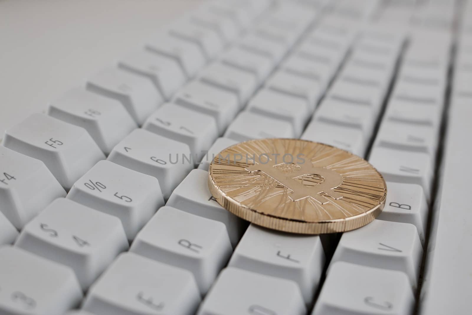 Digital currency physical gold bitcoin coin on white computer keyboard.