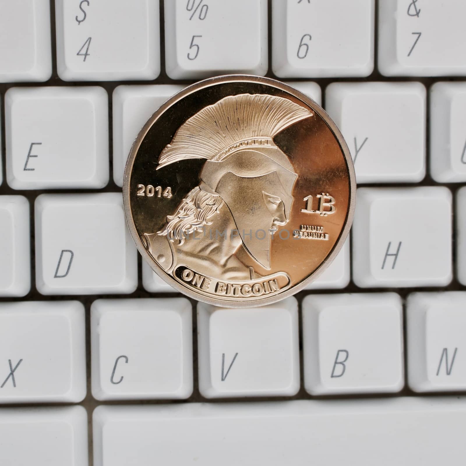 Digital currency physical gold titan bitcoin coin on white computer keyboard.