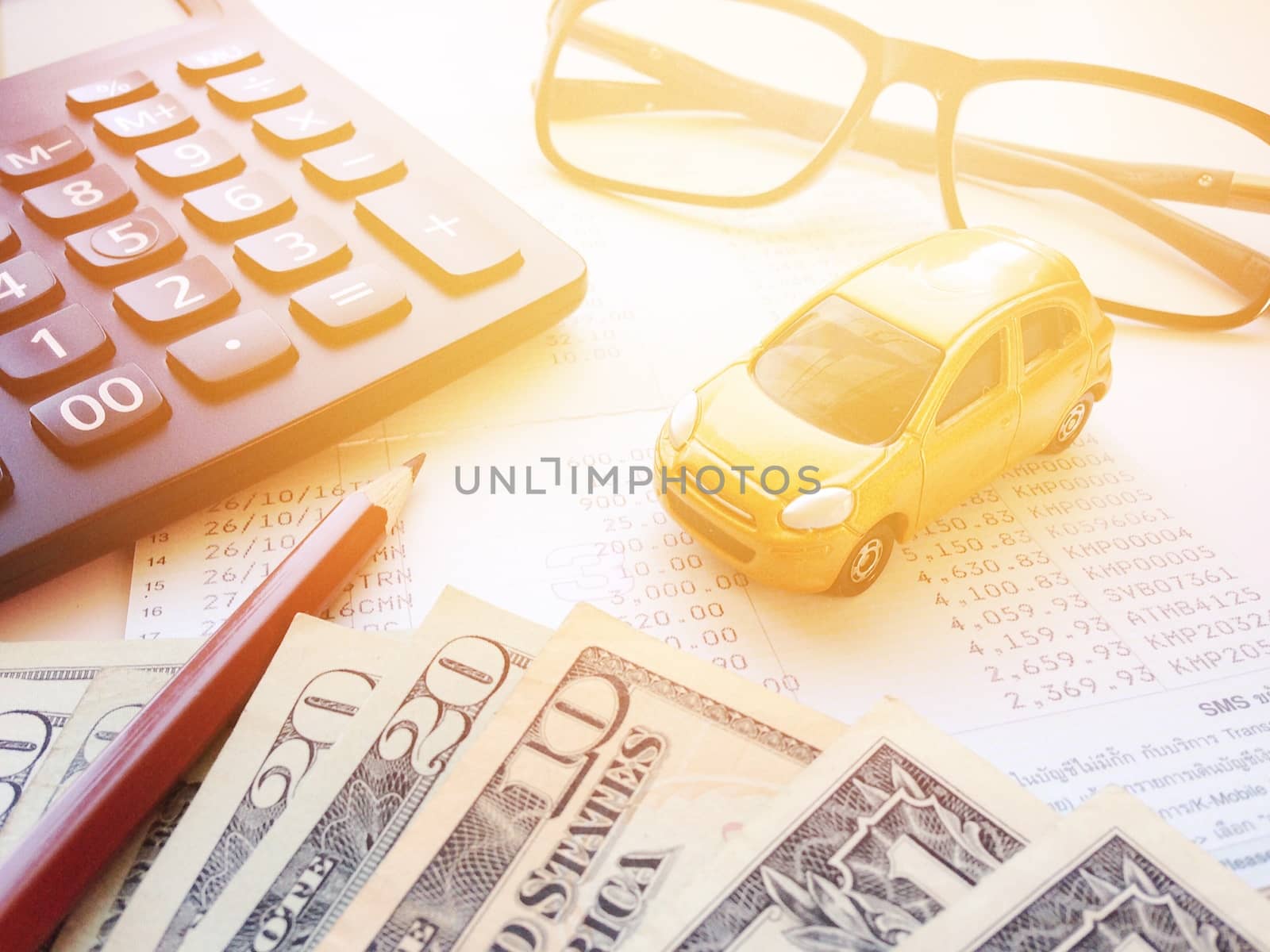 Business, finance, savings, banking or car loan concept : Miniature car model, pencil, money, calculator, eyeglasses and savings account passbook or financial statement on white background