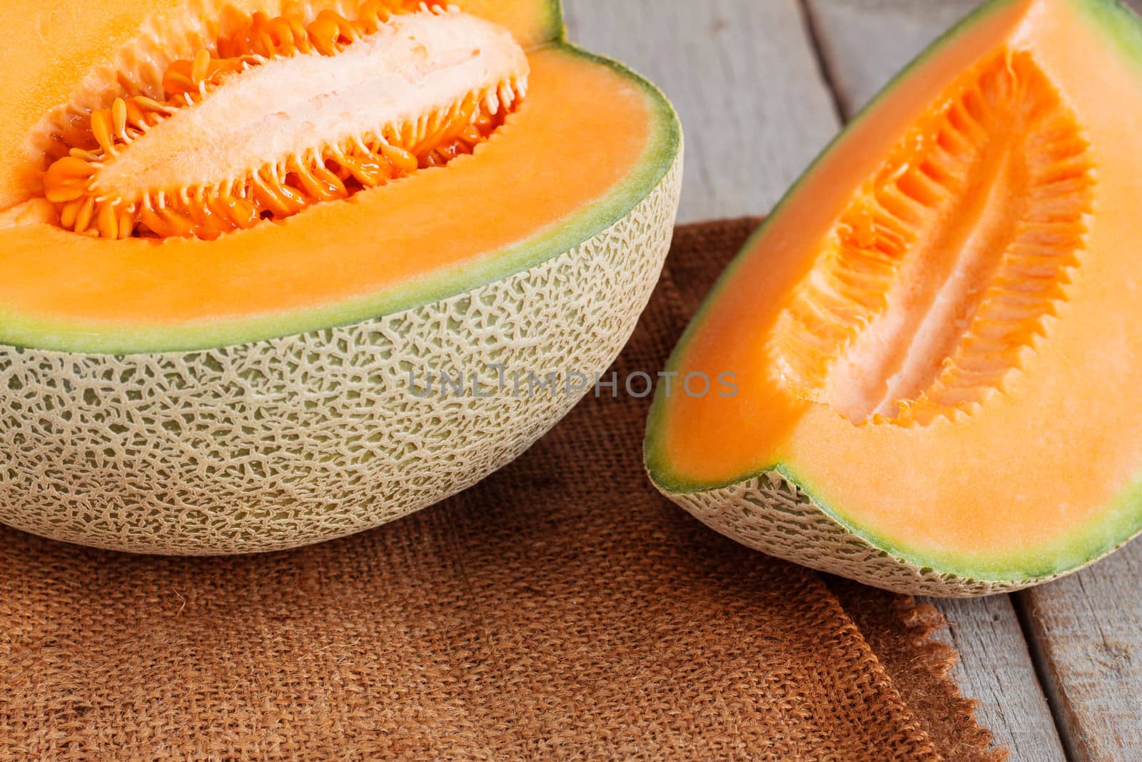 Melon sliced on sack of wooden table.