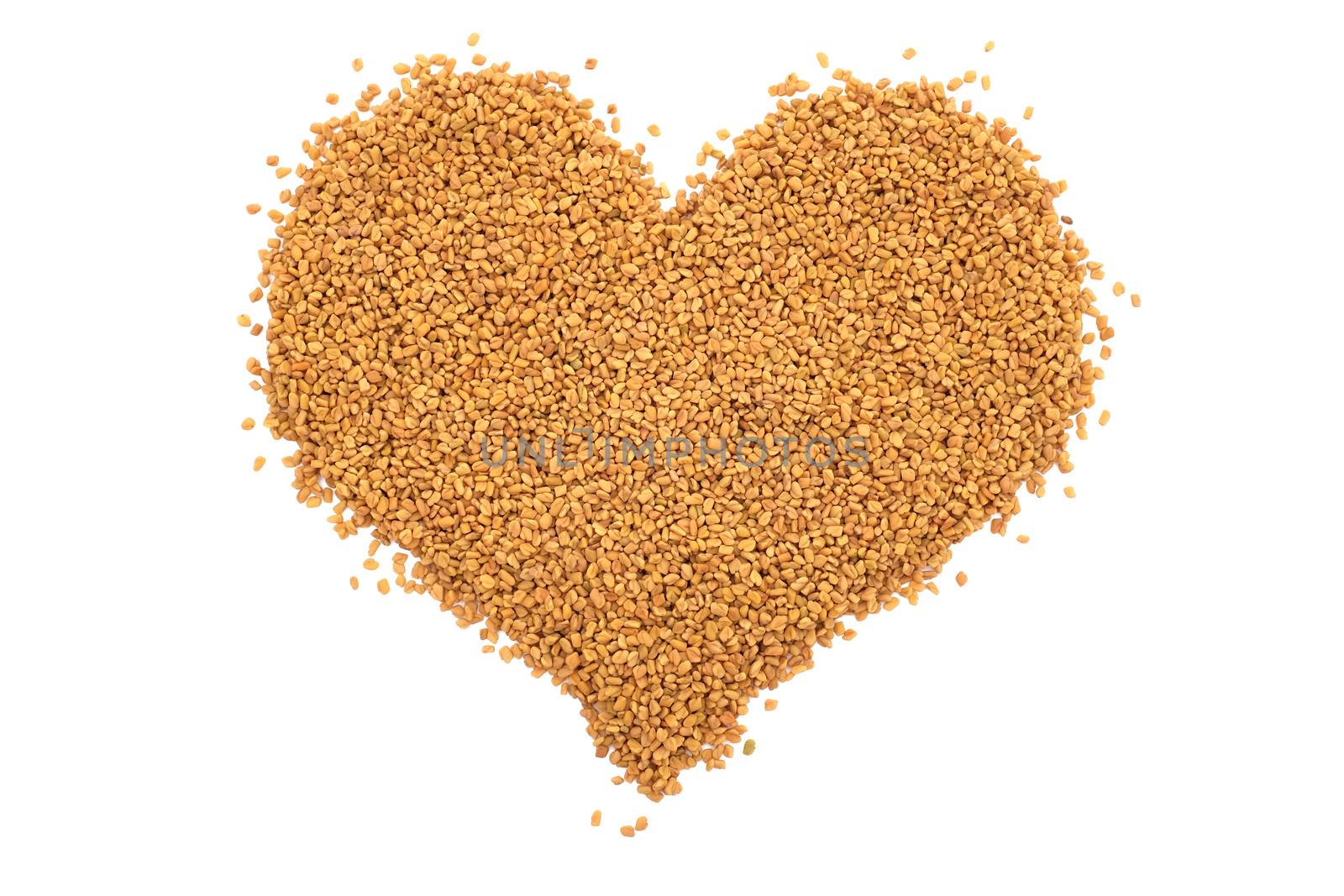 Dried fenugreek seeds in a heart shape, isolated on a white background