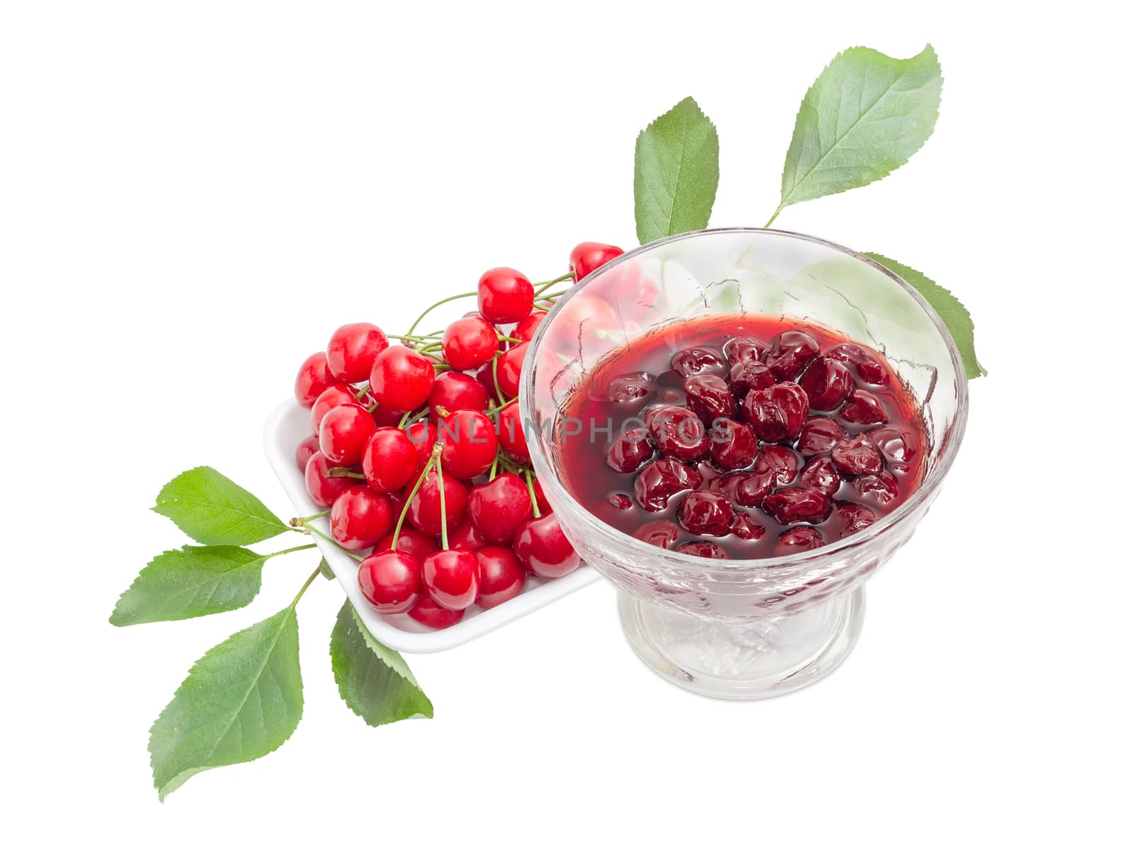 Cherry jam with whole fruits in the glass dessert stem bowl against of the fresh cherries with the stalks and leaves in the foam food container on a light background
