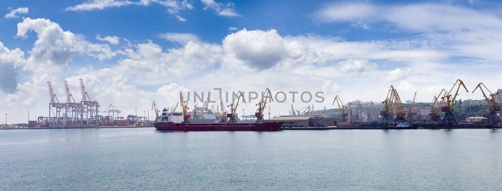 Panorama of the sea cargo port with several berth with different harbor cranes and ship, standing at unloading
