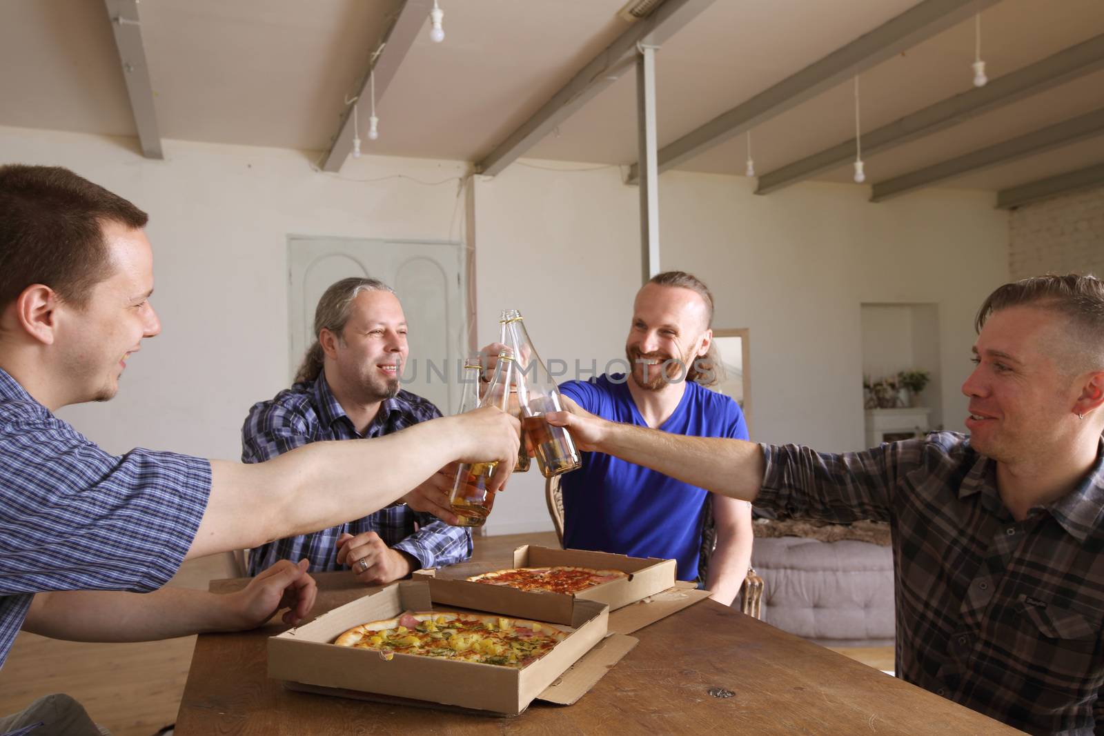 Male friends sitting at home, clink beer, going to eat pizza, celebrating something