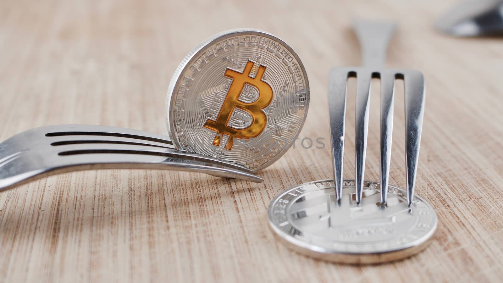 Digital currency physical silver bitcoin coin on wooden board near litecoin.