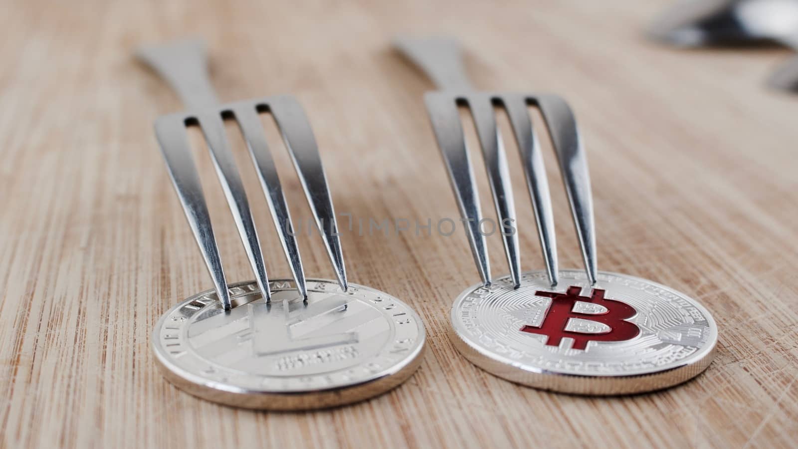 Cryptocurrency physical litecoin coin and bitcoin with fork on wooden board.