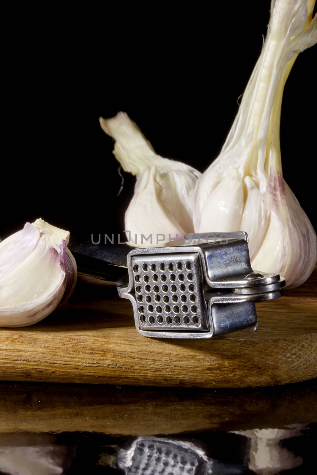 Garlic press and cloves of garlic laid on a wooden table background